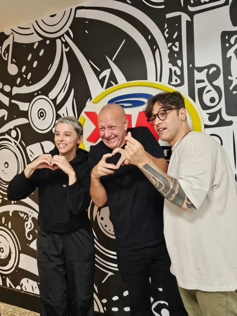 Três pessoas posando com gestos de mãos.